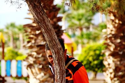 Man hiding behind tree trunk