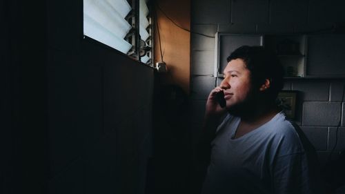 Side view of man talking on phone at home