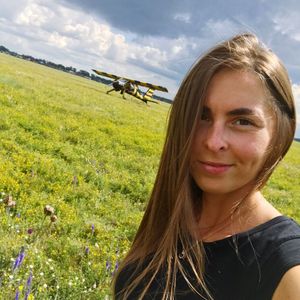 Close-up portrait of smiling young woman on field against sky