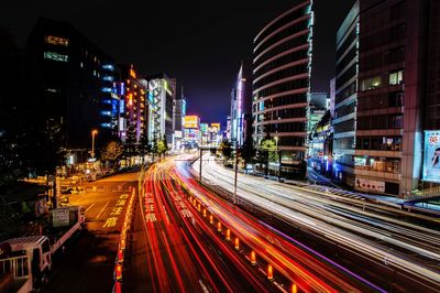 Light trails on city street amidst buildings at night