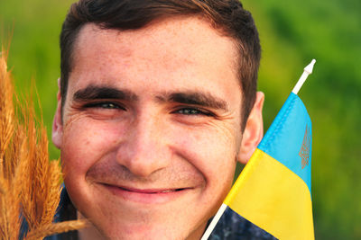 Man with flag of ukraine outdoors. young ukrainian men portrait. bouquet of ripe golden spikelets