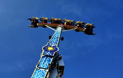 Low angle view of carousel against clear blue sky