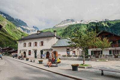 Road by buildings in city against sky