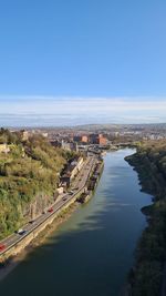 High angle view of river amidst buildings against clear blue sky