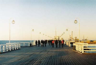 People on pier against clear sky