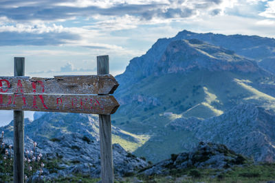 Old wooden road sign against mountain