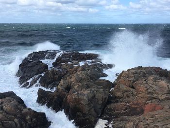 Scenic view of rocks on shore against sky