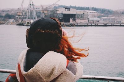 Rear view of woman leaning on railing in front of sea