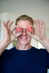 Smiling man holding fruits at home