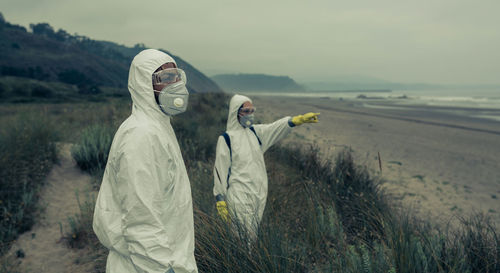 Man and woman wearing pollution mask while standing outdoors