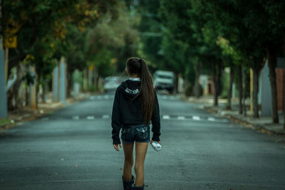 Rear view of woman walking on road