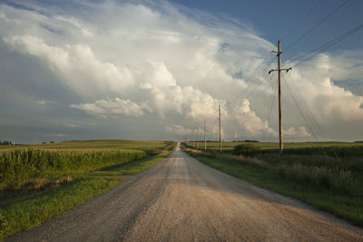 Road amidst field against sky