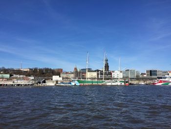 Sea by buildings against blue sky