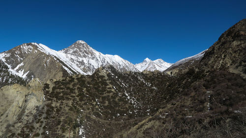 Scenic view of snowcapped mountains against clear blue sky