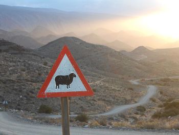 Road sign by mountains against sky