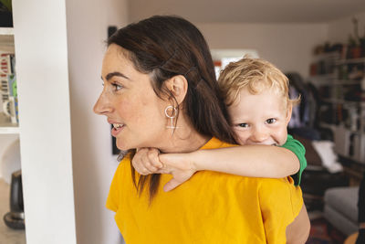 Mother carrying son on back