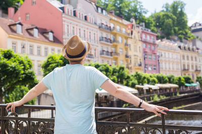 Rear view of man standing by railing in city