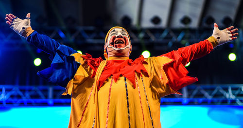 Clown standing with arms outstretched performing on stage