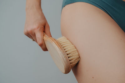 Woman's arm holding dry brush to top of her leg, cellulite treatment and dry brush. 