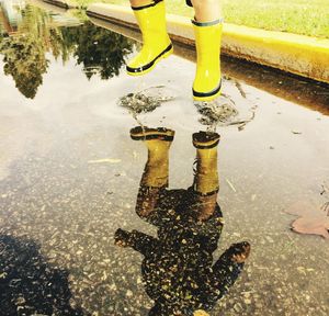 Low section of person standing on wet puddle