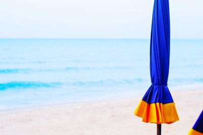 Blue umbrella on beach against sky