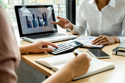 Midsection of woman using laptop on table