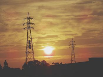 Low angle view of silhouette electricity pylon against sky during sunset