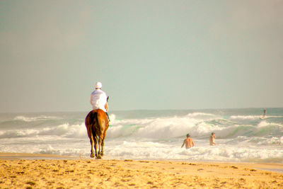 Rear view of man standing on beach against clear sky