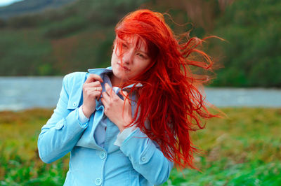 Young woman with redhead holding jacket at lakeshore