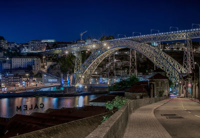 Illuminated bridge over river against sky at night