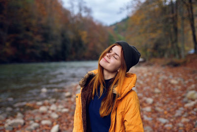 Beautiful young woman standing against trees during autumn