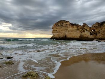 Scenic view of beach against cloudy sky