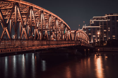 Illuminated bridge over water at night