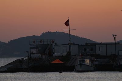 Buildings by sea against sky during sunset