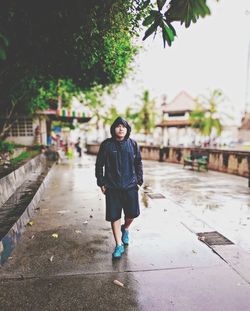 Full length of woman walking on footpath during rainy season