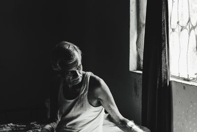 Portrait of man standing by window at home