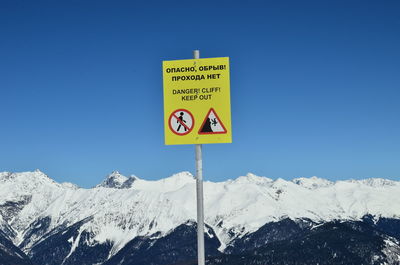 Information sign against snowcapped mountain and clear blue sky