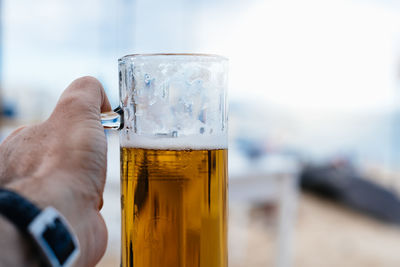 Close-up of hand holding beer glass