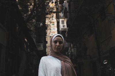 Portrait of woman standing against building in city