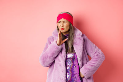 Full length of woman standing against pink background