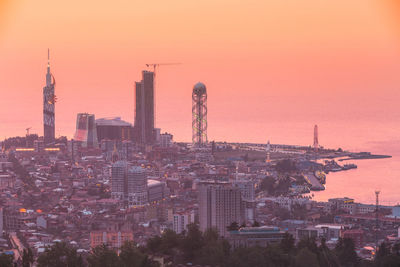 Illuminated cityscape against sky during sunset