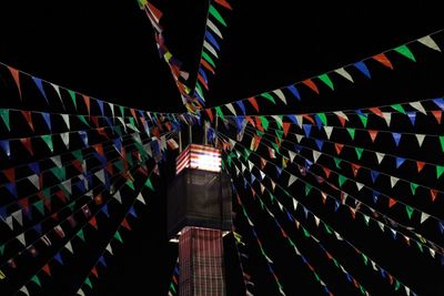 Low angle view of illuminated flags hanging at night