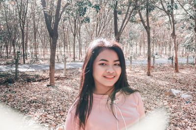 Portrait of smiling young woman standing in forest