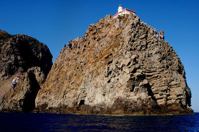 Rock formations by sea against clear blue sky