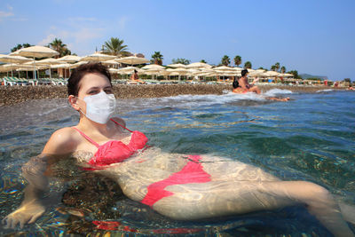 Woman swimming in pool at beach against sky