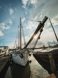 Fishing boat moored at harbor against sky