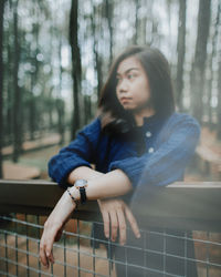 Portrait of young woman sitting on tree in forest