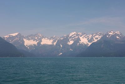 Scenic view of sea by mountain against sky