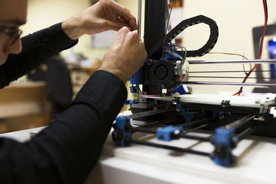 Male engineer fixing 3d printer on table