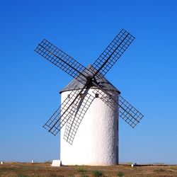 Traditional windmill on field against clear blue sky. quixote